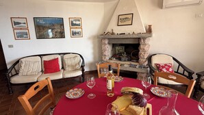 Un coin repas agrémenté d’une cheminée en pierre, d’un canapé et d’une table mise pour le repas.