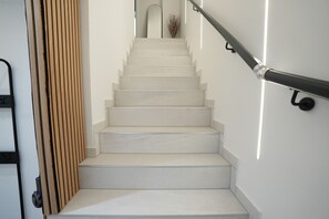 A staircase with a handrail, wooden paneling on one side, and a view of the upper floor.