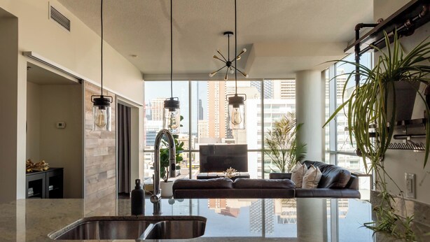 Una cocina moderna con una isla grande, un lavamanos integrado y vistas a la ciudad a través de amplias ventanas.