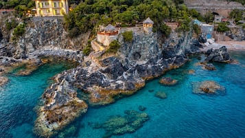 Ein Küstenanwesen mit einer Steintreppe, die zu einem Gebäude führt, klarem türkisblauem Wasser und üppiger Vegetation.