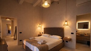 A modern bedroom with a large bed, bedside tables, a mirror, and a bathroom with a sink and mirror. - Roc Villa - 2 Private Beach Accesses  (Rosignano Marittimo)