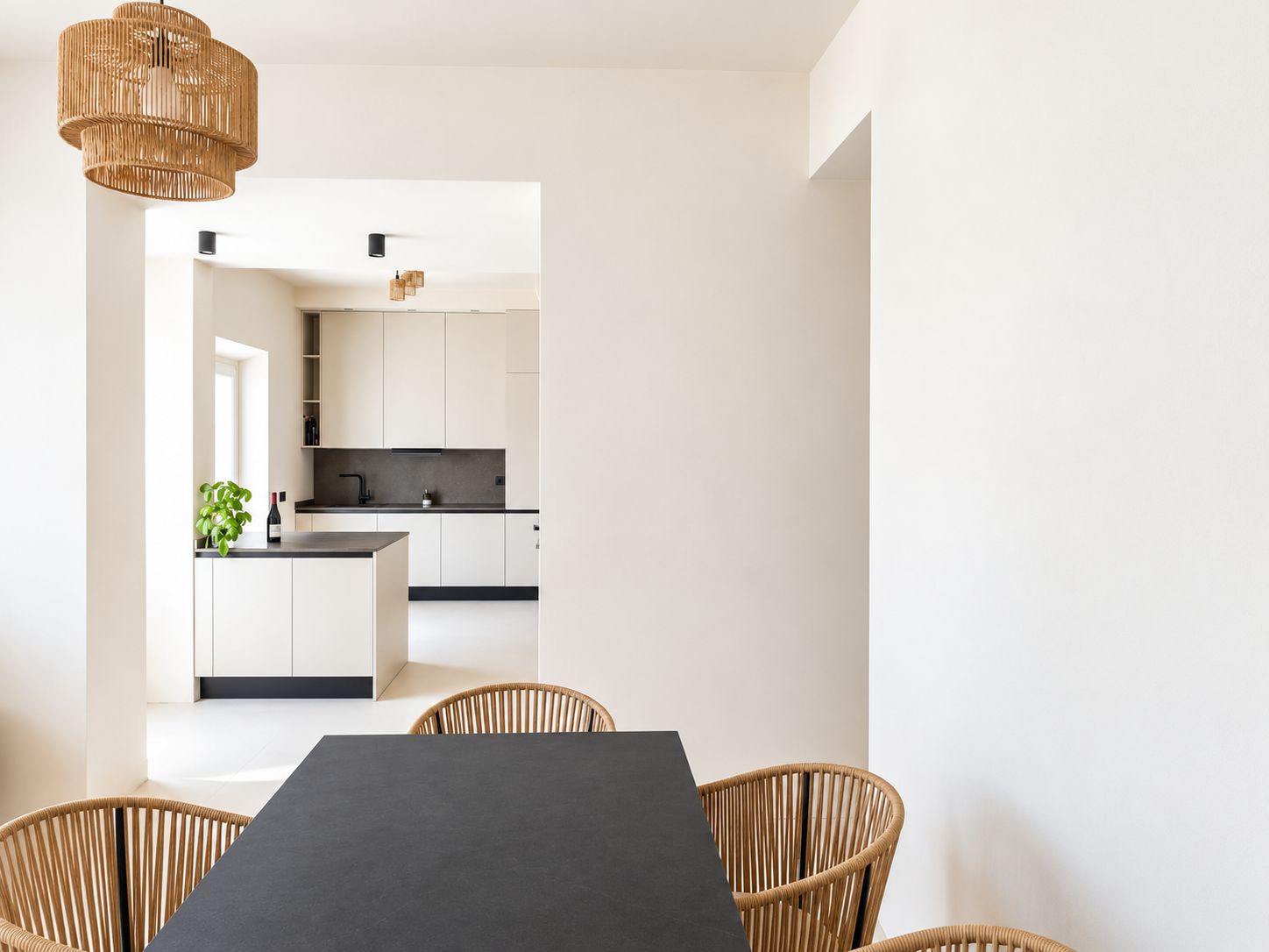 Una cucina moderna con mobili bianchi, un piano di lavoro nero e un lampadario.