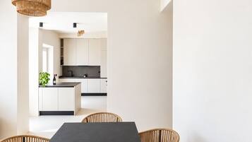 Una cucina moderna con mobili bianchi, un piano di lavoro nero e un lampadario.