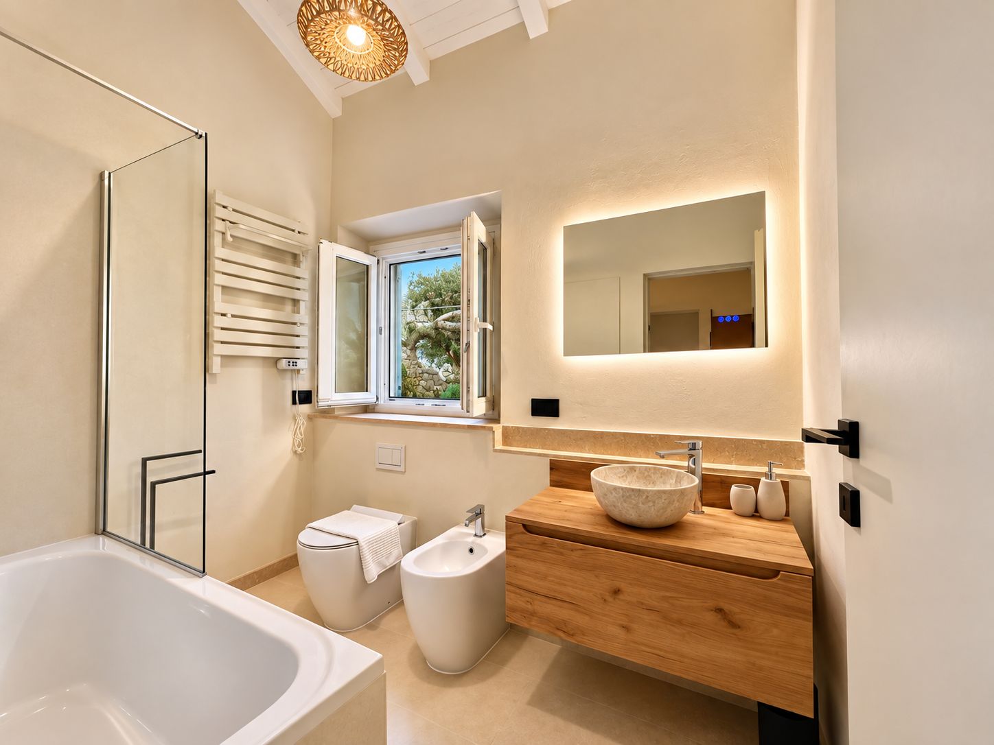A modern bathroom with a bathtub, bidet, and a vanity with a large mirror.