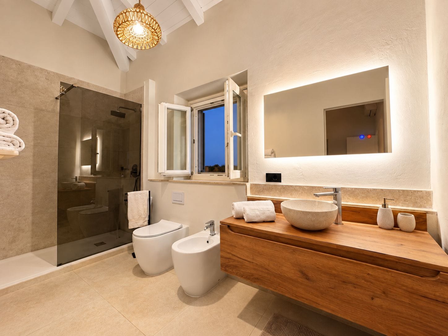 Ein modernes Badezimmer mit einer Duschkabine aus Glas, Toilette, Bidet und einem Holzwaschtisch mit großem Spiegel und Aufsatzbecken.