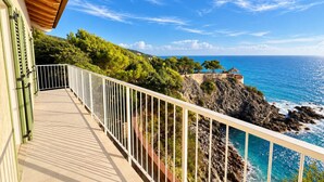 A balcony with a view of the sea and rocky coastline.