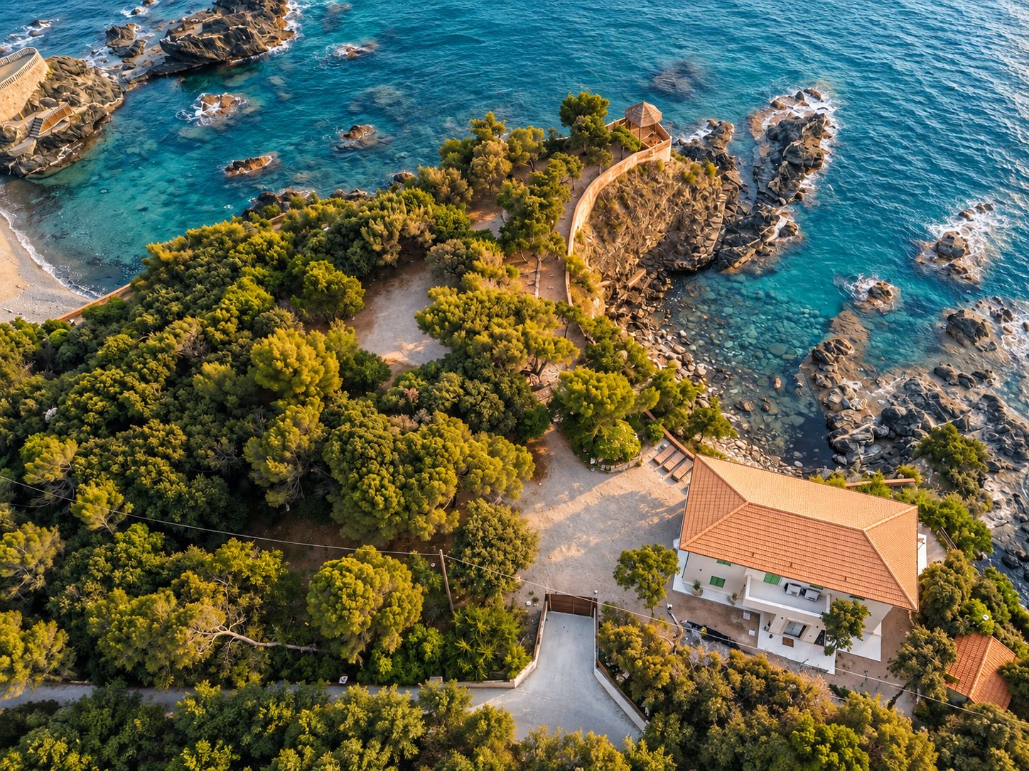 Una proprietà costiera con un ampio giardino, una piscina e vista sul mare.