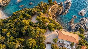Una proprietà costiera con un ampio giardino, una piscina e vista sul mare.