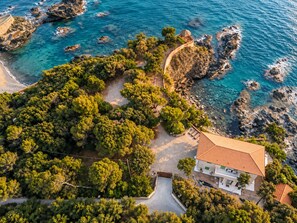 A coastal property with a large garden, a swimming pool, and a view of the sea.