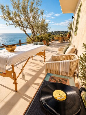 A terrace with a table, chairs, a record player, and a view of the sea. - Roc Villa - 2 Private Beach Accesses  (Rosignano Marittimo)