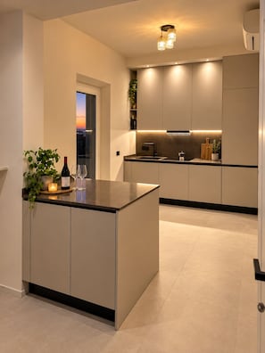 A modern kitchen with a central island, recessed lighting, and a view of the cityscape. - Roc Villa - 2 Private Beach Accesses  (Rosignano Marittimo)