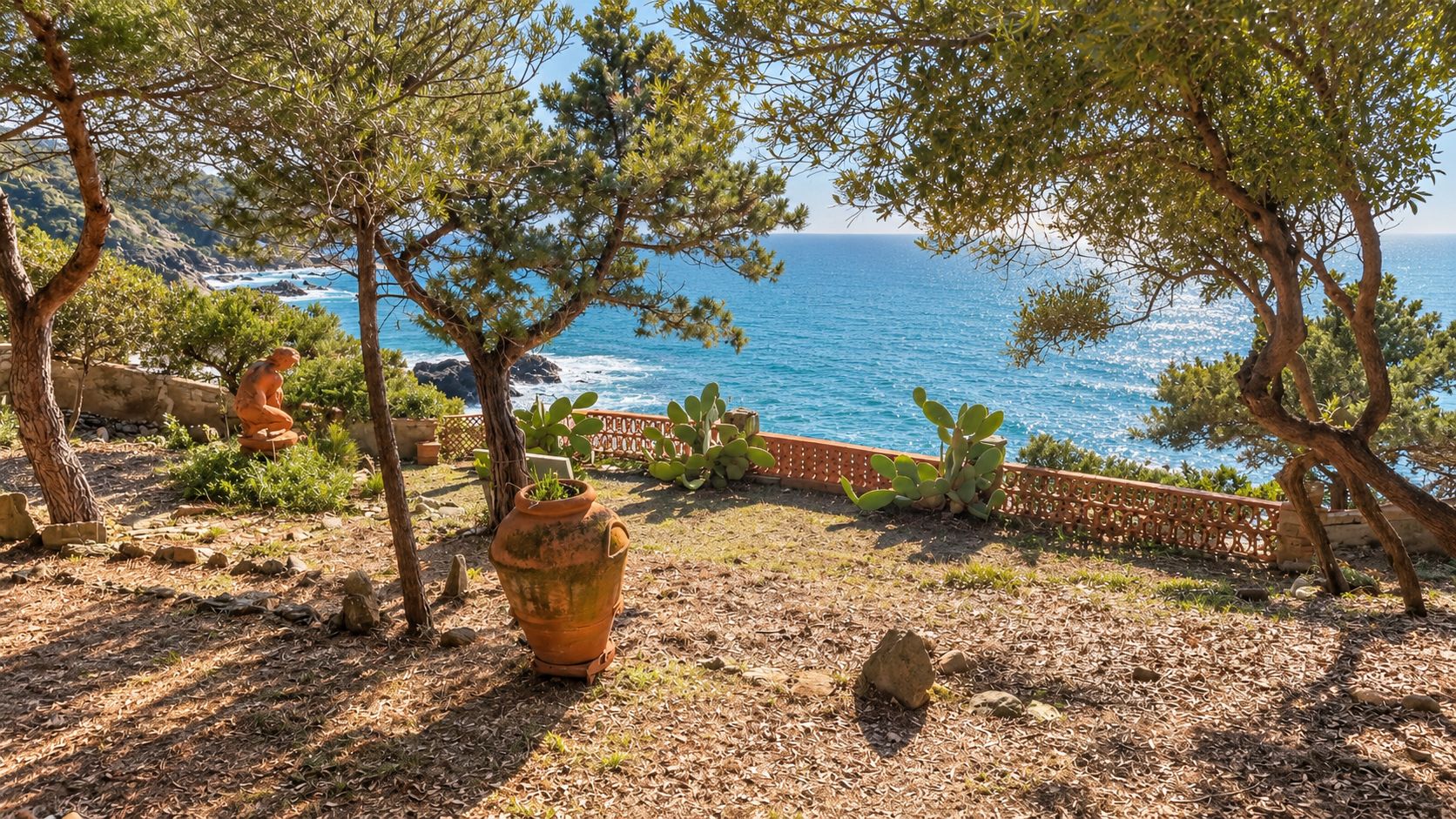 A coastal garden with a view of the sea, featuring potted plants, a large terracotta pot, and a stone wall.