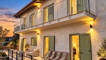 A two-story building with a balcony, outdoor seating, and a well-lit entrance.