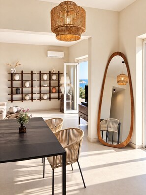 A modern interior with a dining area, wicker chairs, a large mirror, and a view through a glass door. - Roc Villa - 2 Private Beach Accesses (Rosignano Marittimo)