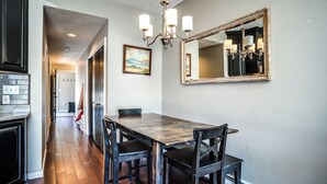 A dining area with a wooden table and chairs, a chandelier, and a large mirror on the wall. - Tenney Mountain Retreat, Plymouth & Rumney, NH (Plymouth)