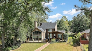 A two-story house with a brick exterior, large windows, and a covered front porch.