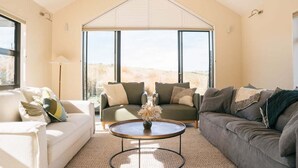 Ein geräumiges Wohnzimmer mit zwei Sofas, einem Couchtisch und einem großen Fenster mit Blick ins Freie.