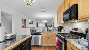 A modern kitchen with wooden cabinets, stainless steel appliances, and a marble countertop. - Entire home in prime Raleigh with workspace, comm pool, dog park and golf course (Raleigh)