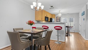 A modern kitchen with wooden cabinets, a central island, and red bar stools. - Entire home in prime Raleigh with workspace, comm pool, dog park and golf course (Raleigh)