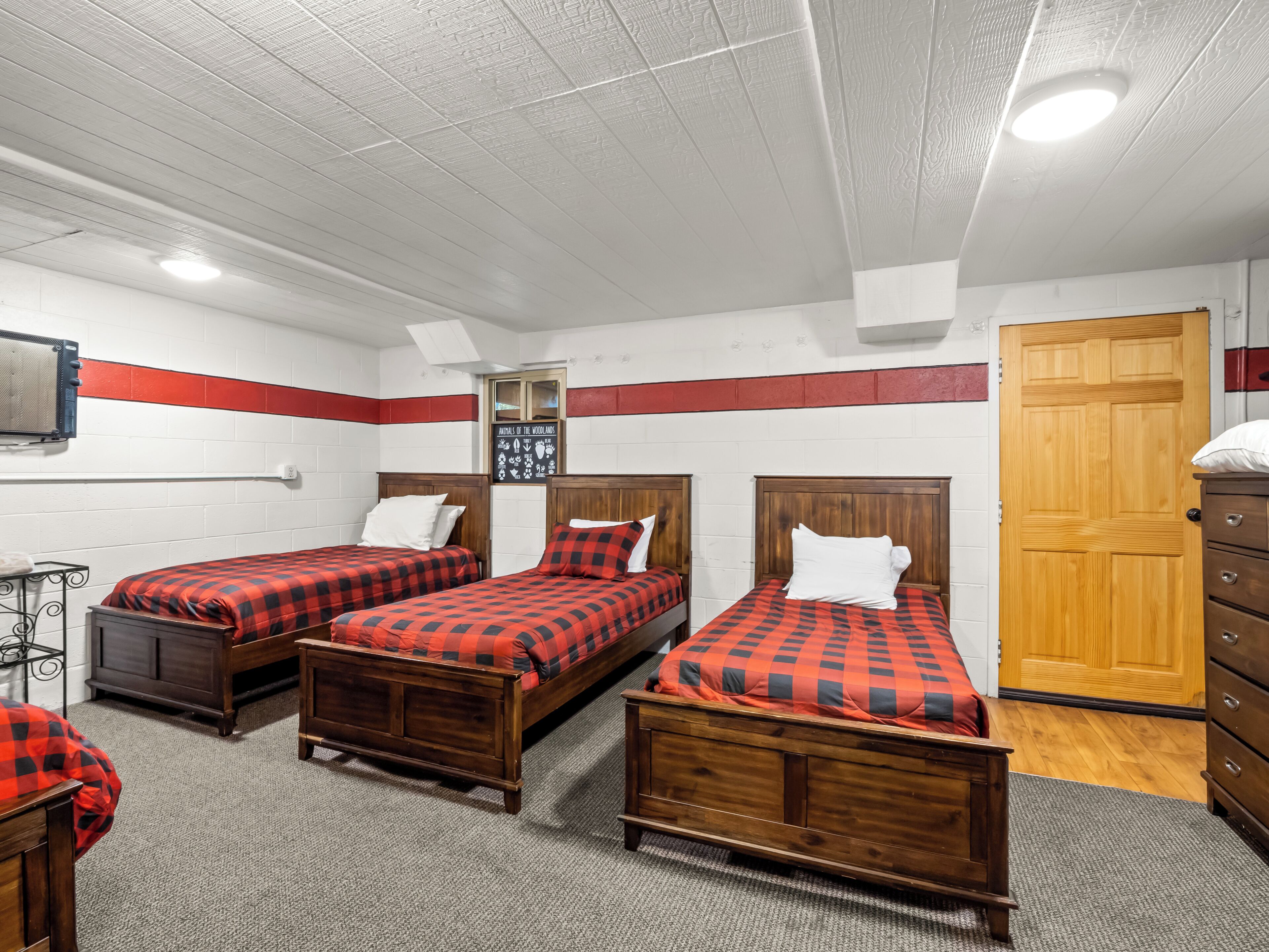 A room with three wooden beds, a wooden wardrobe, a wall-mounted radiator, and a door.