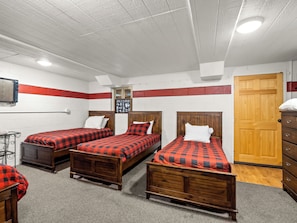 A room with three wooden beds, a wooden wardrobe, a wall-mounted radiator, and a door.