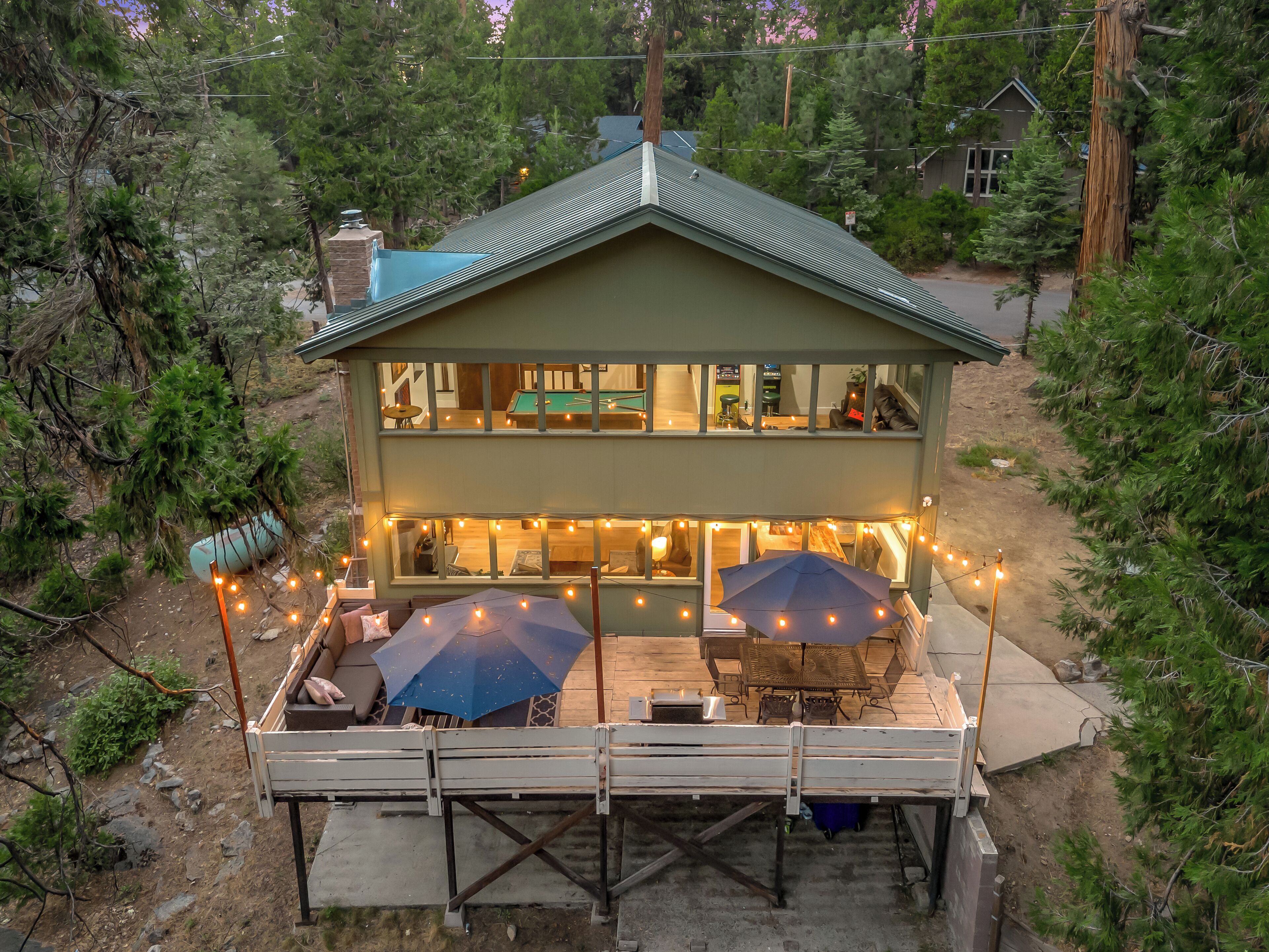 A two-story house with a deck, outdoor seating, and string lights.