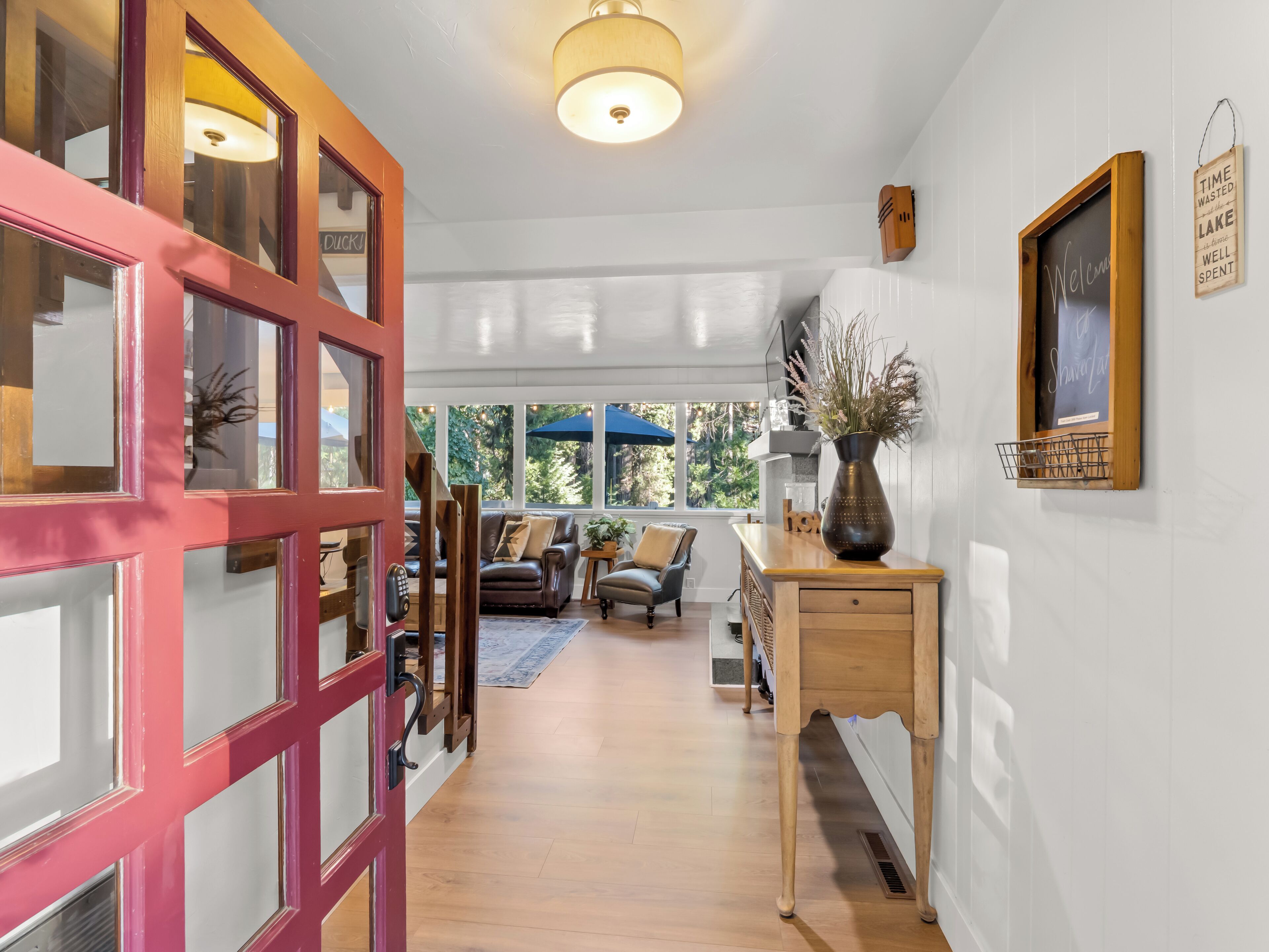 A hallway with a wooden desk, a vase, and a welcome sign.