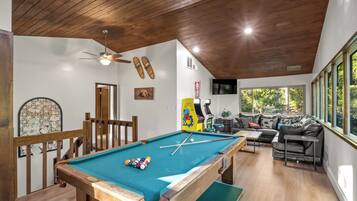 A pool table with balls, a ceiling fan, a sofa, and a TV.