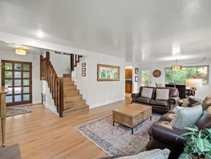 Un vaste espace de vie agrémenté d’un escalier en bois, d’un canapé en cuir, d’une table basse et d’un tapis.