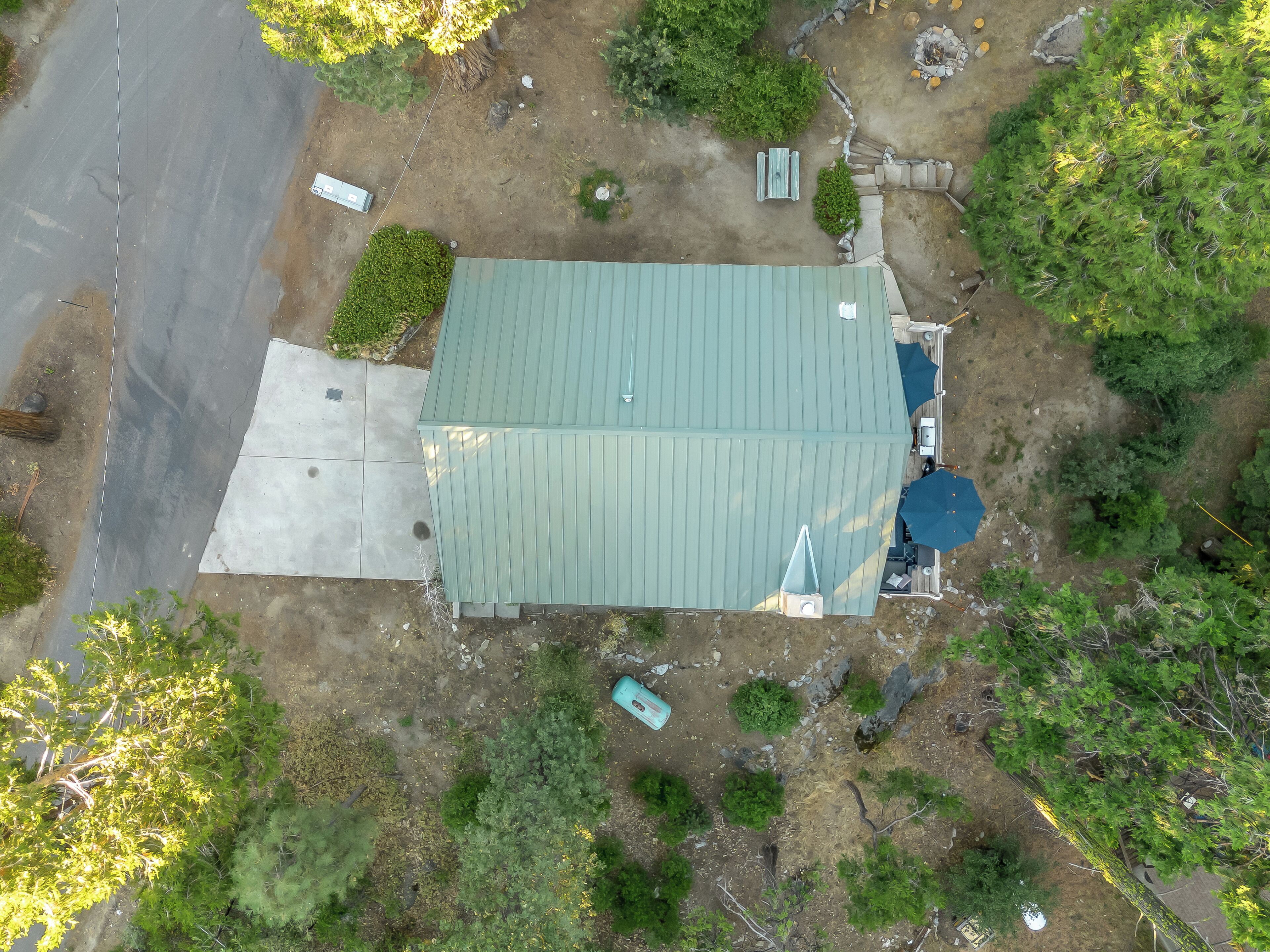 An aerial view of a property with a large building, a paved driveway, and surrounding greenery.