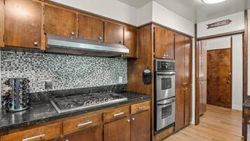 A kitchen with wooden cabinets, a stainless steel range, and a tiled backsplash.