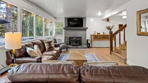 A modern living room with a fireplace, leather sofas, a coffee table, and a TV mounted on the wall.
