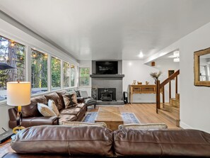 Una sala de estar moderna con chimenea, sofás de cuero, una mesa de centro y un televisor montado en la pared.
