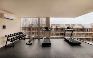A gym with treadmills, dumbbells, and a bench.
