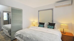 A modern hotel room with a large bed, two bedside tables with lamps, a wardrobe with frosted glass doors, and a large mirror on the wall. - Cedar Rest Studio (Katoomba)