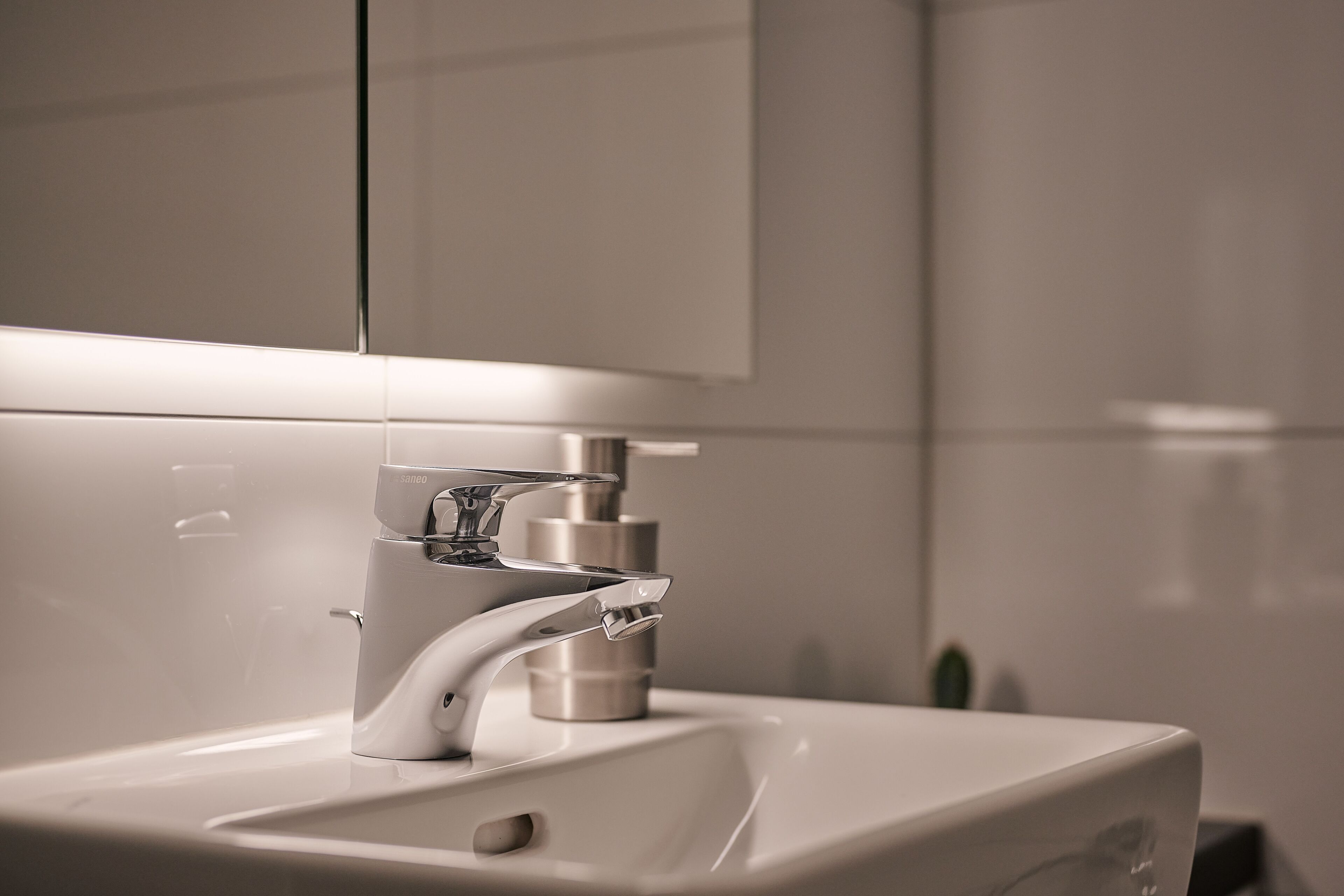 A modern bathroom sink with a chrome faucet and a mirror above it.