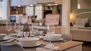 Taula de dinar coberta amb plats blancs, bols i copes de vi, una ampolla de vi i una tovallola.
