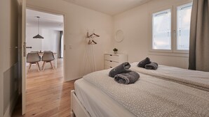 Un dormitori amb dos llits, una taula de nit, un mirall i una finestra amb cortines.