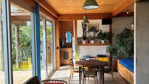 A spacious room with a wooden ceiling, a dining area with a table and chairs, and a large window offering a view of the outdoors. - 'The Dogbox' Architectural home in Central Whanganui. (Whanganui)
