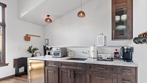 A modern kitchen with dark wooden cabinets, a white countertop, and two pendant lights. - The Loft in Bellerive (Coeur d'Alene)
