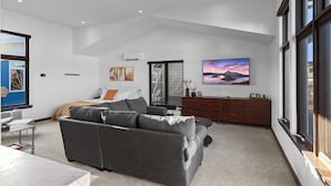 A spacious living room with a large gray sofa, a wooden cabinet, and a flat-screen TV on the wall. - The Loft in Bellerive (Coeur d'Alene)