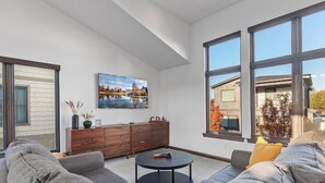 A modern living room with a sectional sofa, a coffee table, and a painting on the wall. - The Loft in Bellerive (Coeur d'Alene)