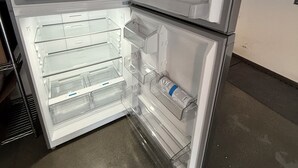 An open refrigerator with multiple shelves and a water dispenser. - The Loft in Bellerive (Coeur d'Alene)