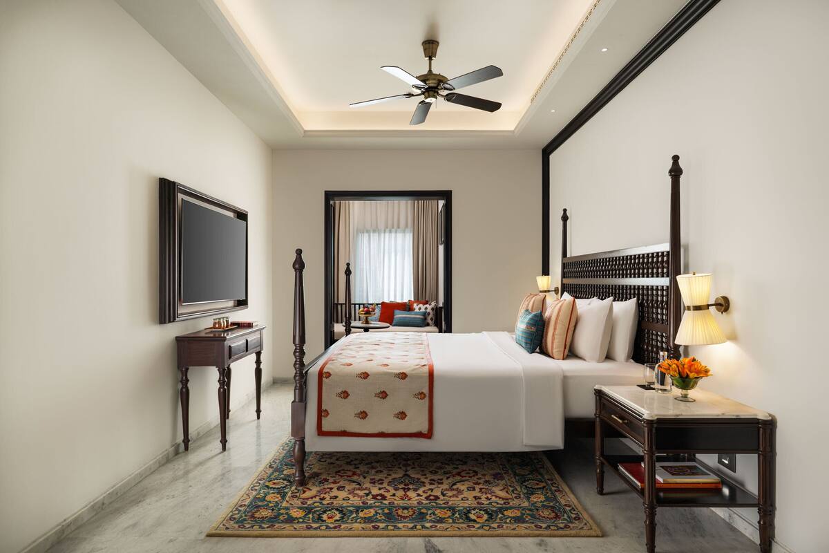 A hotel room with a bed, bedside table, lamp, and a ceiling fan.