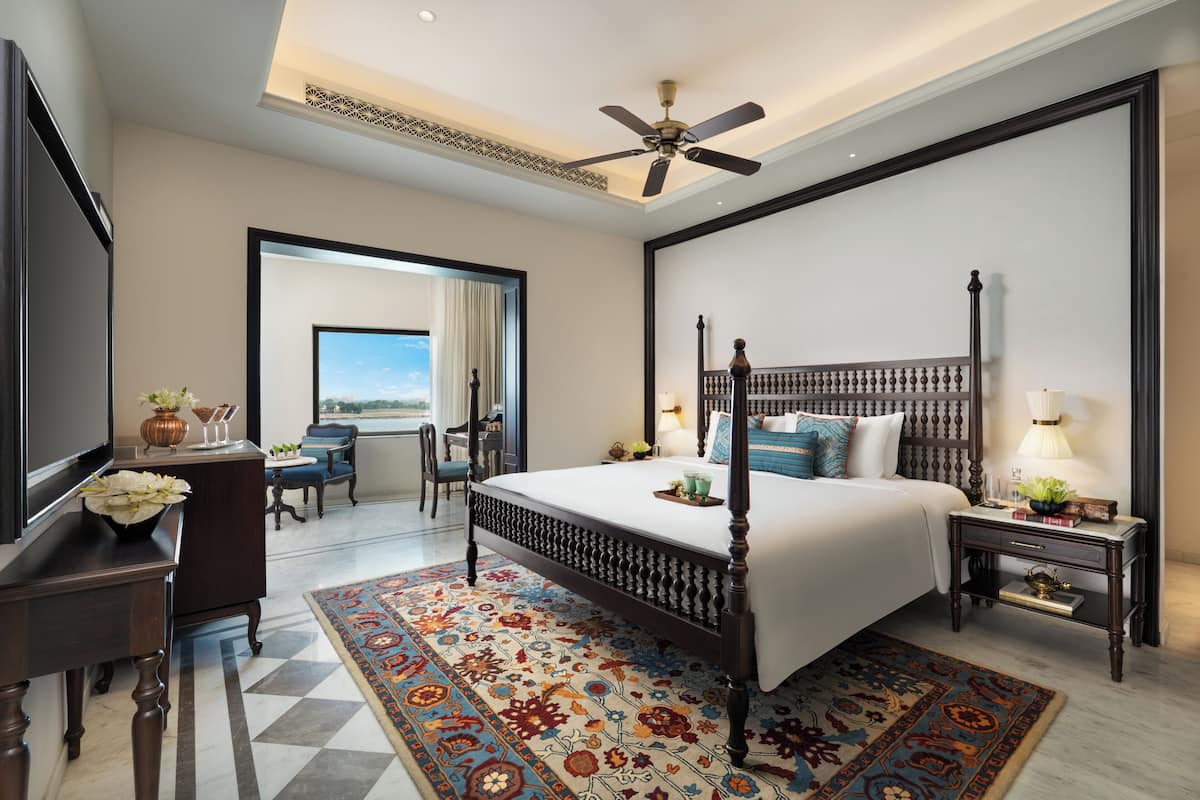 A hotel room with a large bed, a ceiling fan, a television, a desk, and a view of the outdoors.