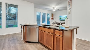 Une cuisine moderne avec des meubles en bois, un lave-vaisselle encastré et un grand îlot central doté d’un évier.