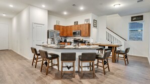 Une cuisine spacieuse dotée d’un grand îlot central, de meubles en bois et d’un design moderne.