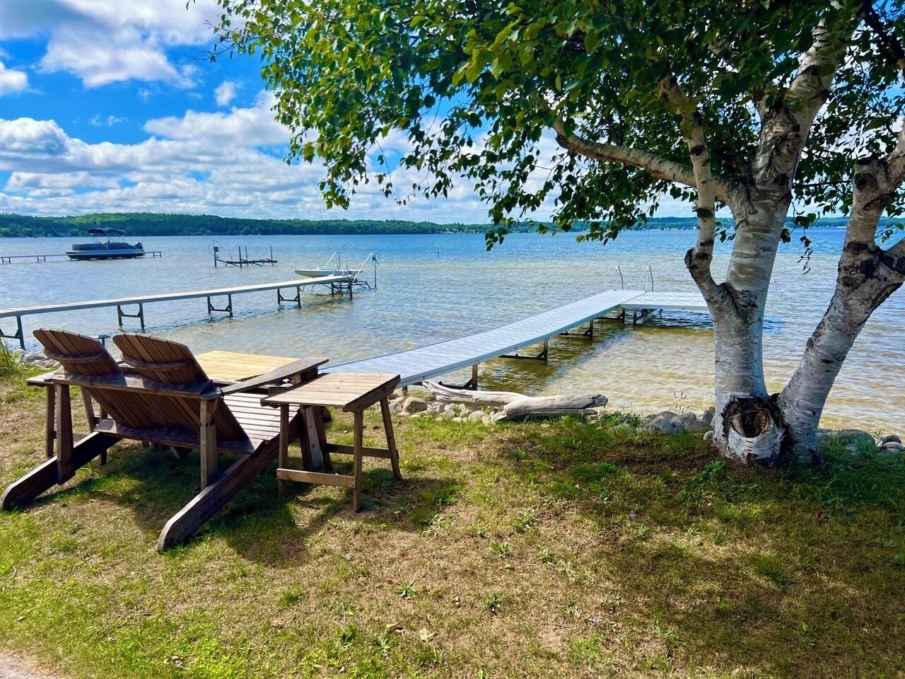 A lakeside setting with a dock, chairs, and a picnic table.