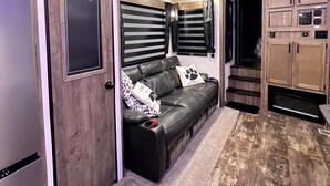 A compact living space with a kitchenette, a sofa, and a small staircase. - The Bear Retreat at Venus (Highlands County)