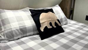 A bed with a checkered bedspread and two pillows, one with a black and beige design. - The Bear Retreat at Venus (Highlands County)